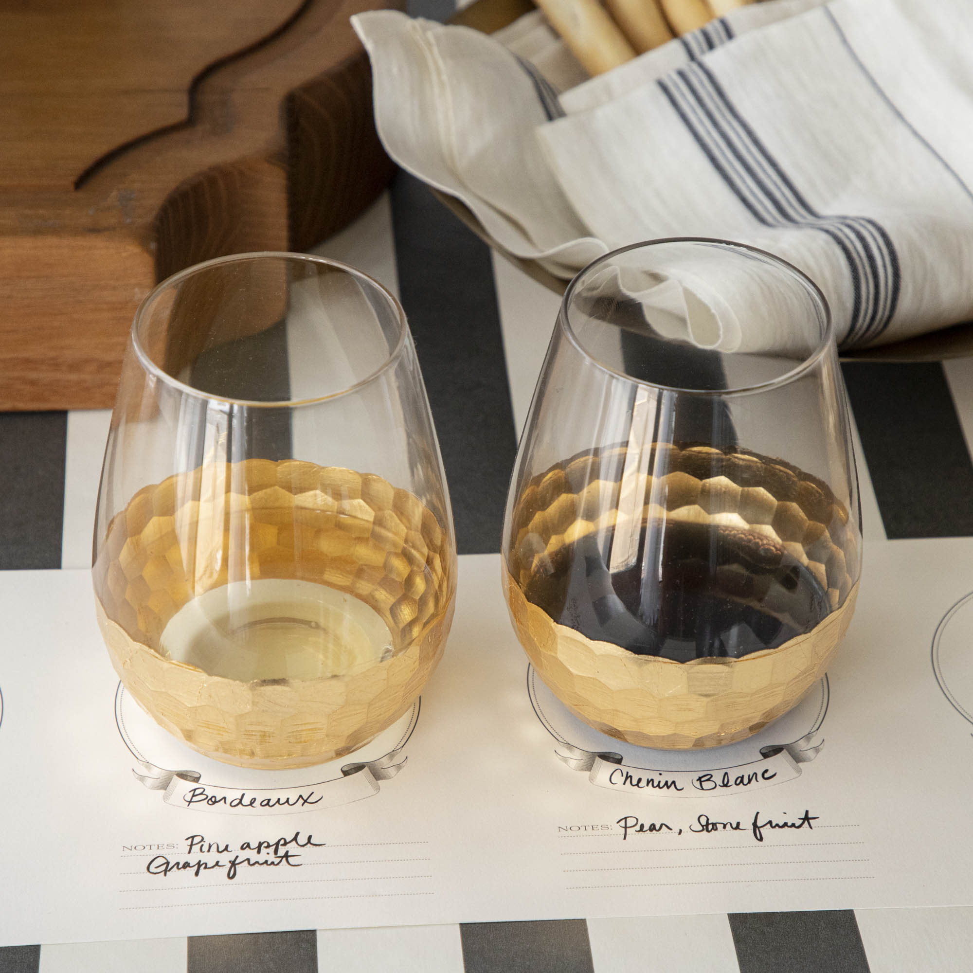 A table setting with Vitorrio Stemless Glassware plates, and napkins.