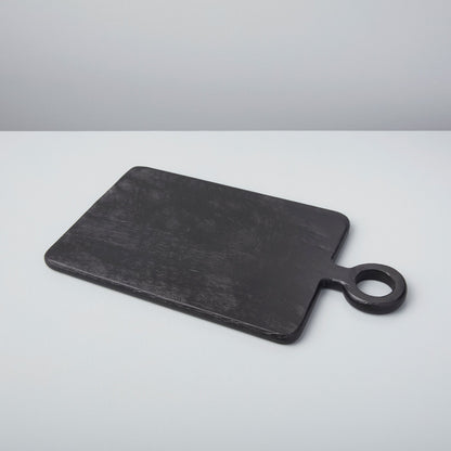 A set of three Be Home Blackened Serving Boards of different shapes and sizes with fresh vegetables displayed in front of a window.