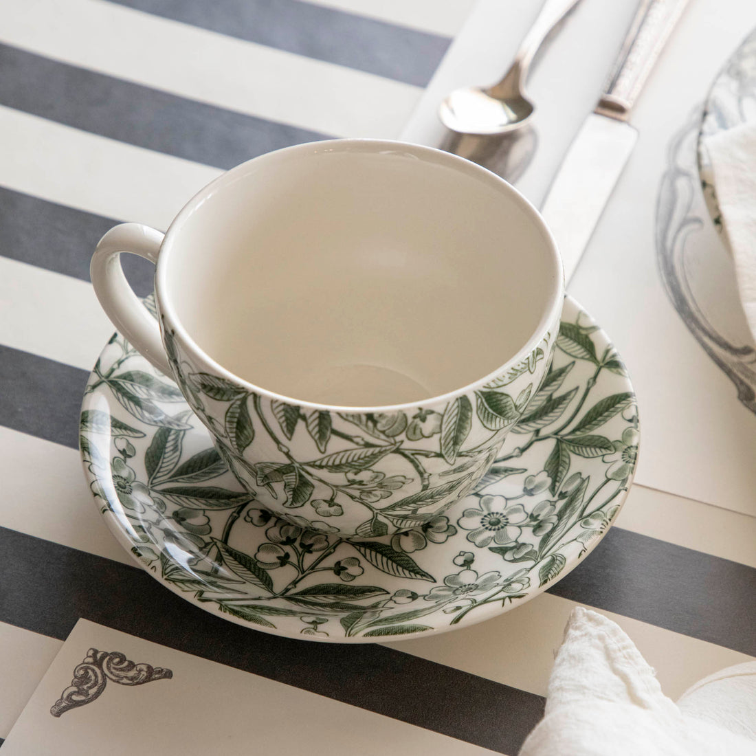 Elegant table setting with Burleigh Green Prunus Dinnerware plates and green striped tablecloth.