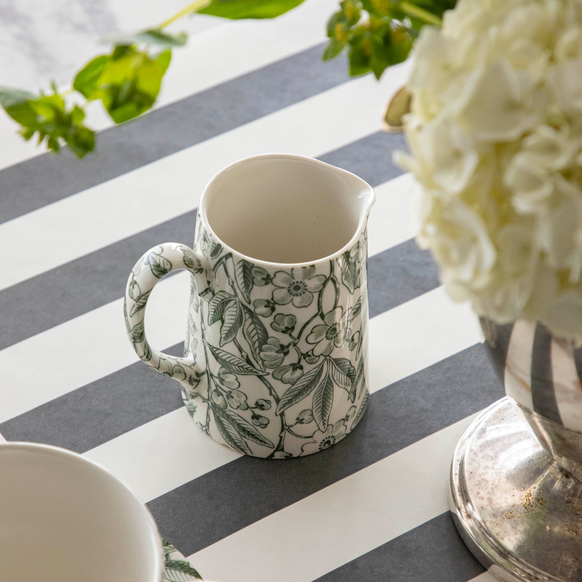 Elegant table setting with Burleigh Green Prunus Dinnerware plates and green striped tablecloth.