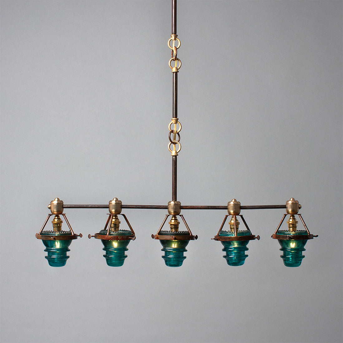 A Telegraph Pendant Lighting with four glass shades and antique insulators hanging from a brass frame. (Brand Name: Hester &amp; Cook)