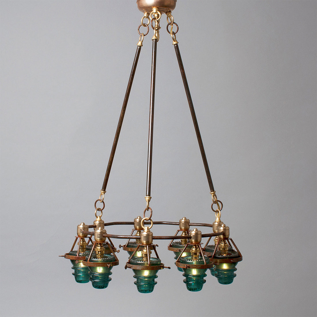 Antique bronze chandelier with multiple glass lampshades and antique insulators suspended from the ceiling, made in the USA by Hester &amp; Cook&