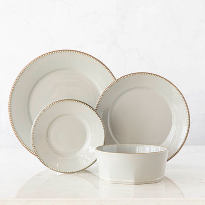 A set of fine stoneware plates and bowls from the Luzia Ash Grey Round Dinnerware collection by Costa Nova on a white surface, perfect for a modern table setting.