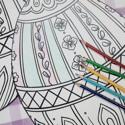 The Die-cut Coloring Easter Egg Placemat on an Easter-themed table setting, partially filled in with colored pencils. 