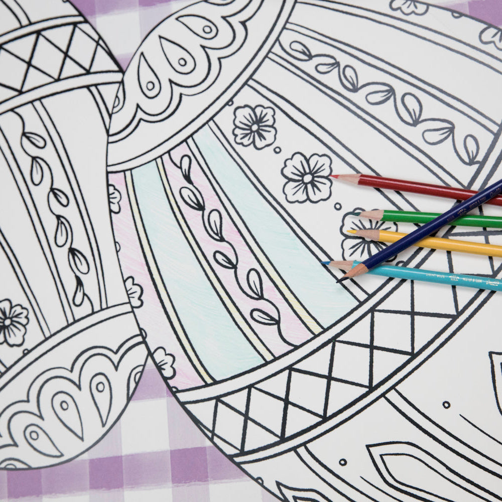 Close-up of the Die-cut Coloring Easter Egg Placemat on an Easter-themed table setting, partially filled in with colored pencils.