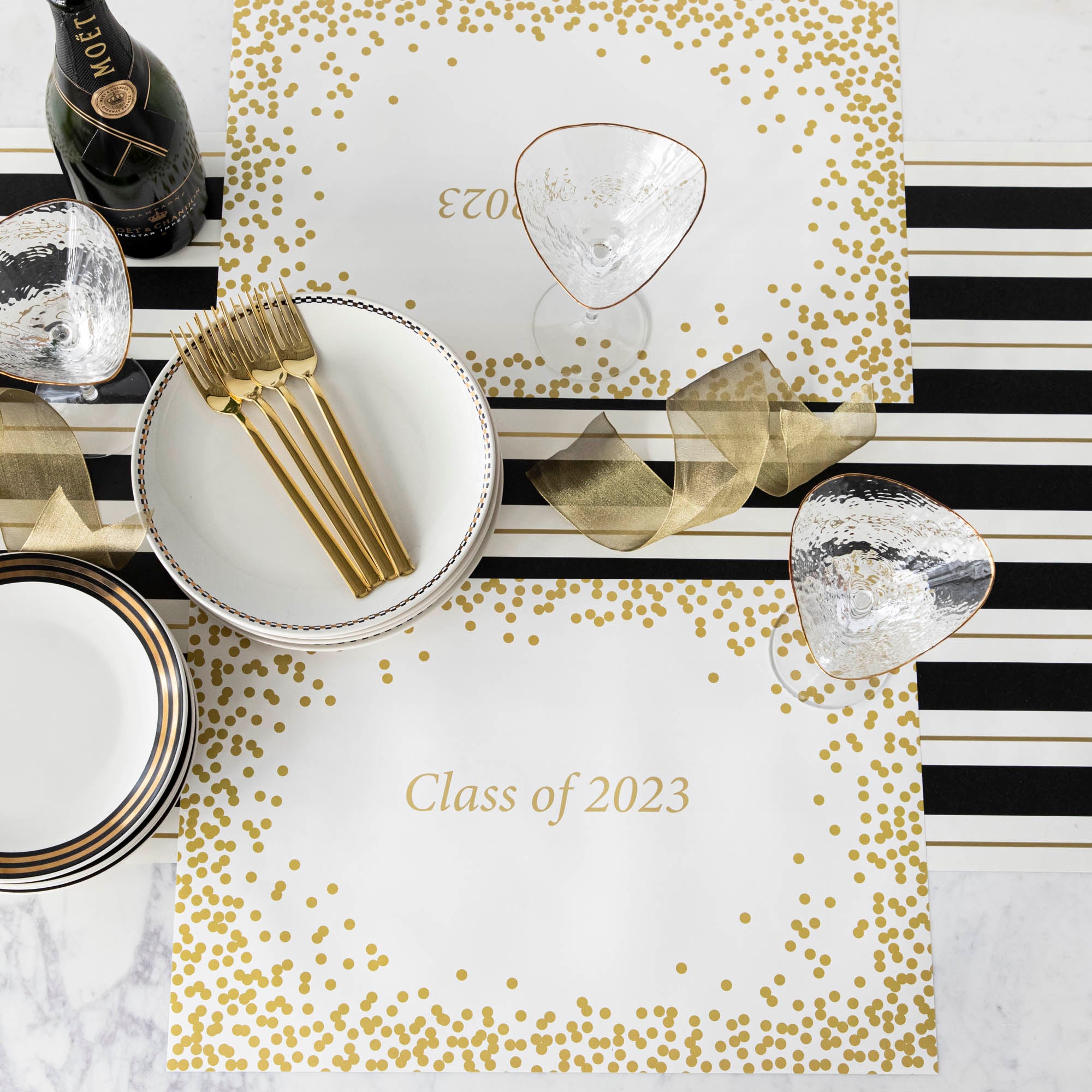 Table setting with Gold Confetti Placemat with personalized message printed in gold color: &quot;Class of 2023&quot;.