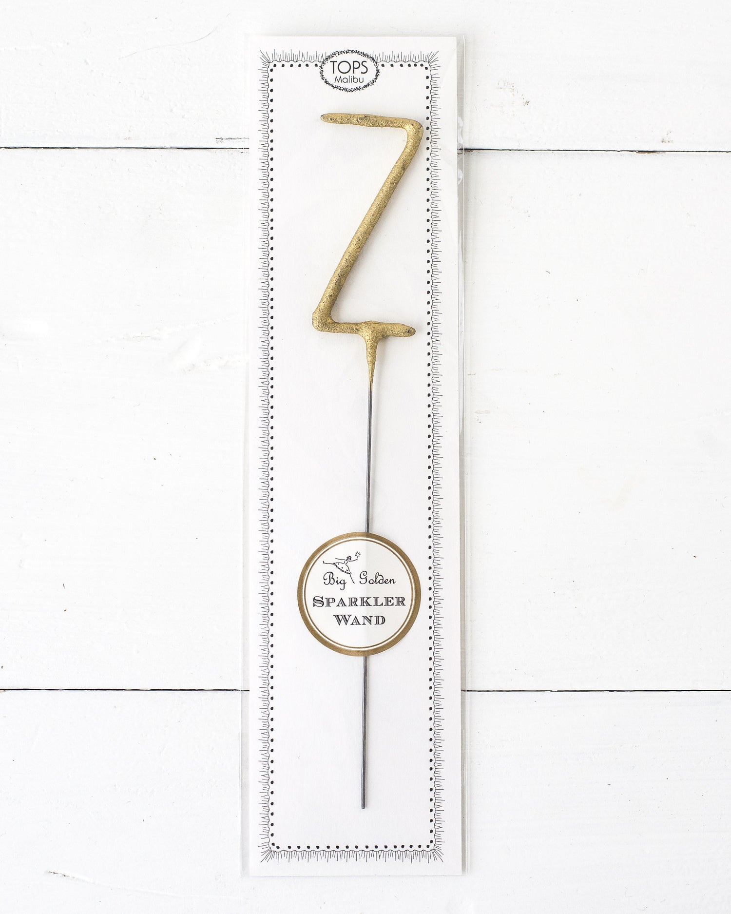 Three Tops Malibu gold Letter Sparklers on a wooden surface.