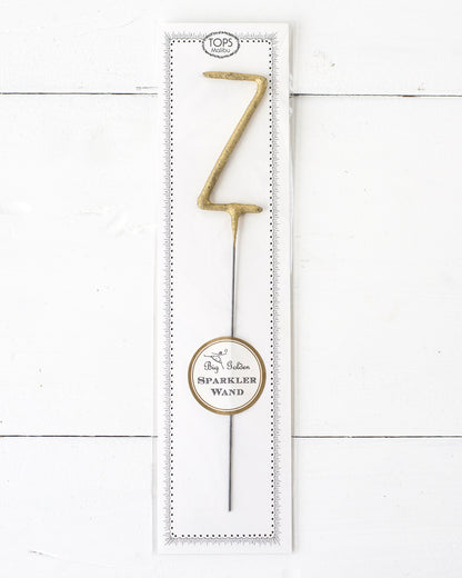 Three Tops Malibu gold Letter Sparklers on a wooden surface.