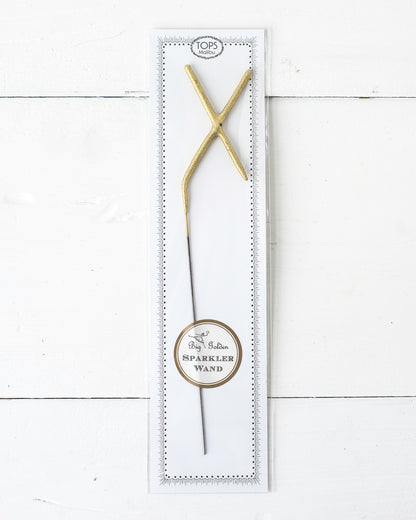 Three Tops Malibu gold Letter Sparklers on a wooden surface.