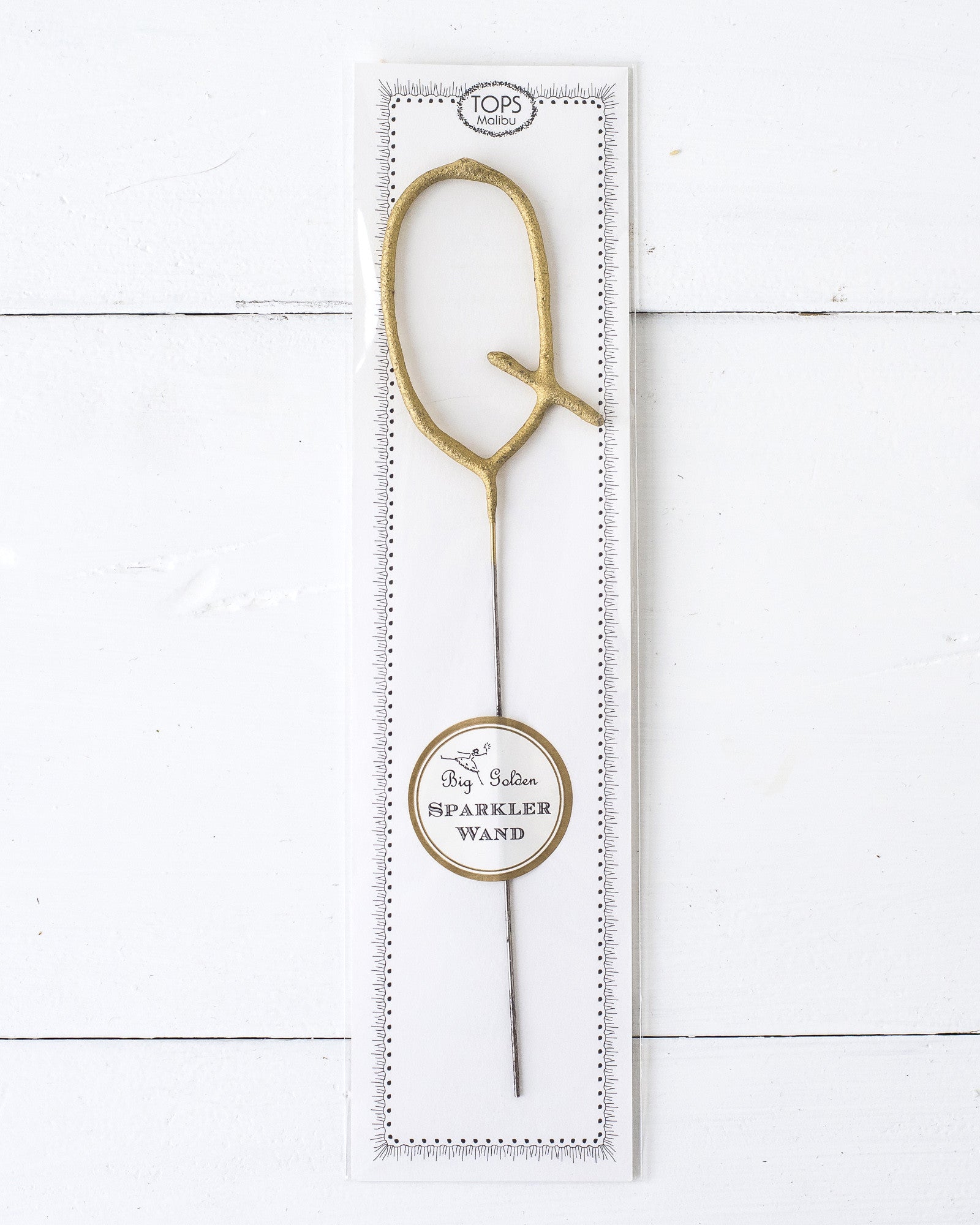 Three Tops Malibu gold Letter Sparklers on a wooden surface.