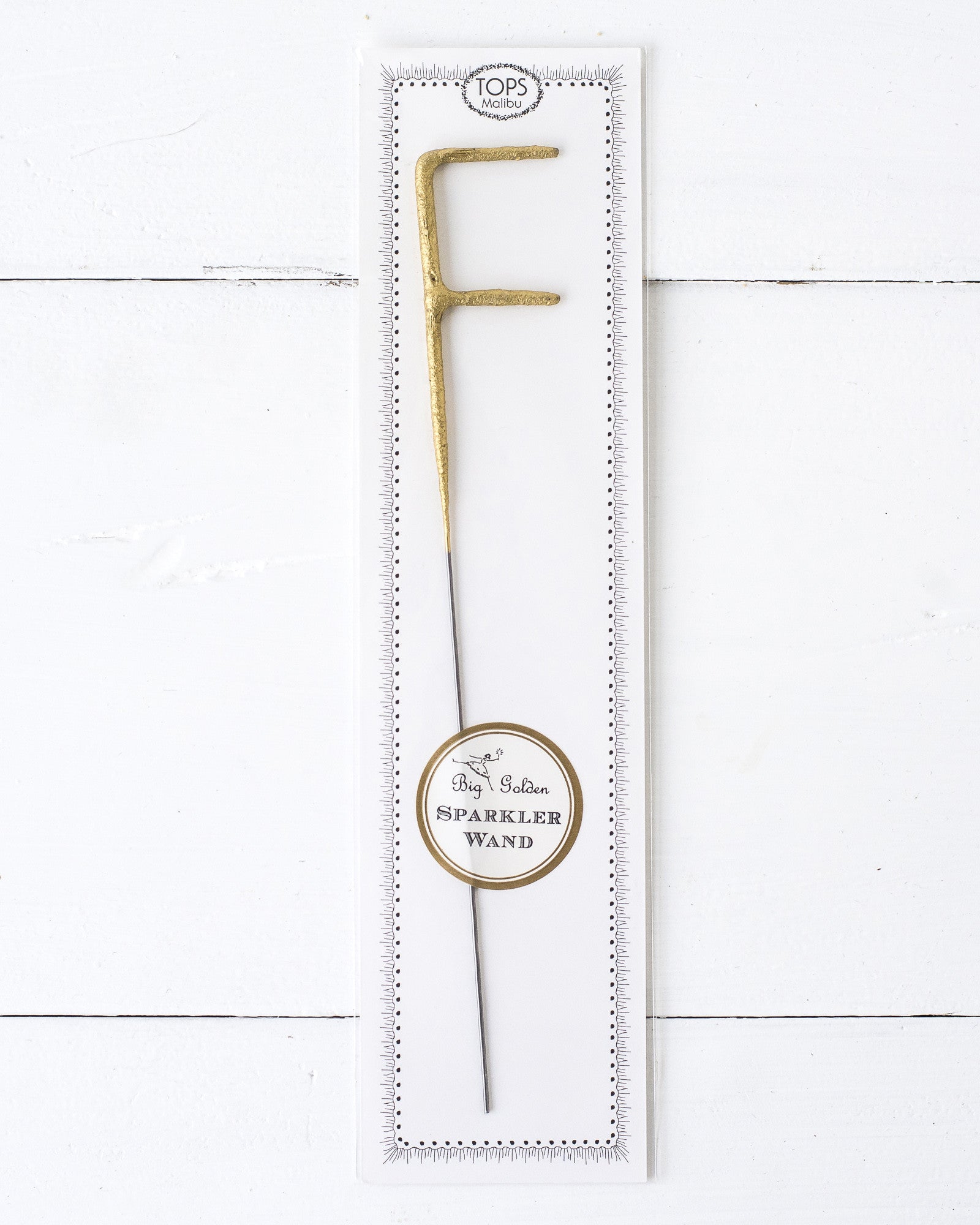 Three Tops Malibu gold Letter Sparklers on a wooden surface.