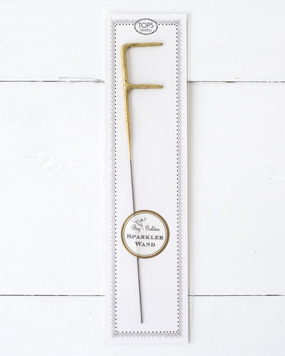 Three Tops Malibu gold Letter Sparklers on a wooden surface.