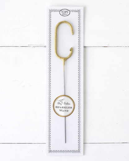 Three Tops Malibu gold Letter Sparklers on a wooden surface.