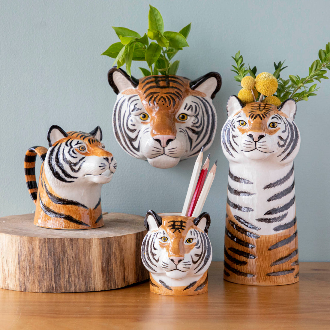 A set of quirky Quail tiger ceramic vases on a wooden table.