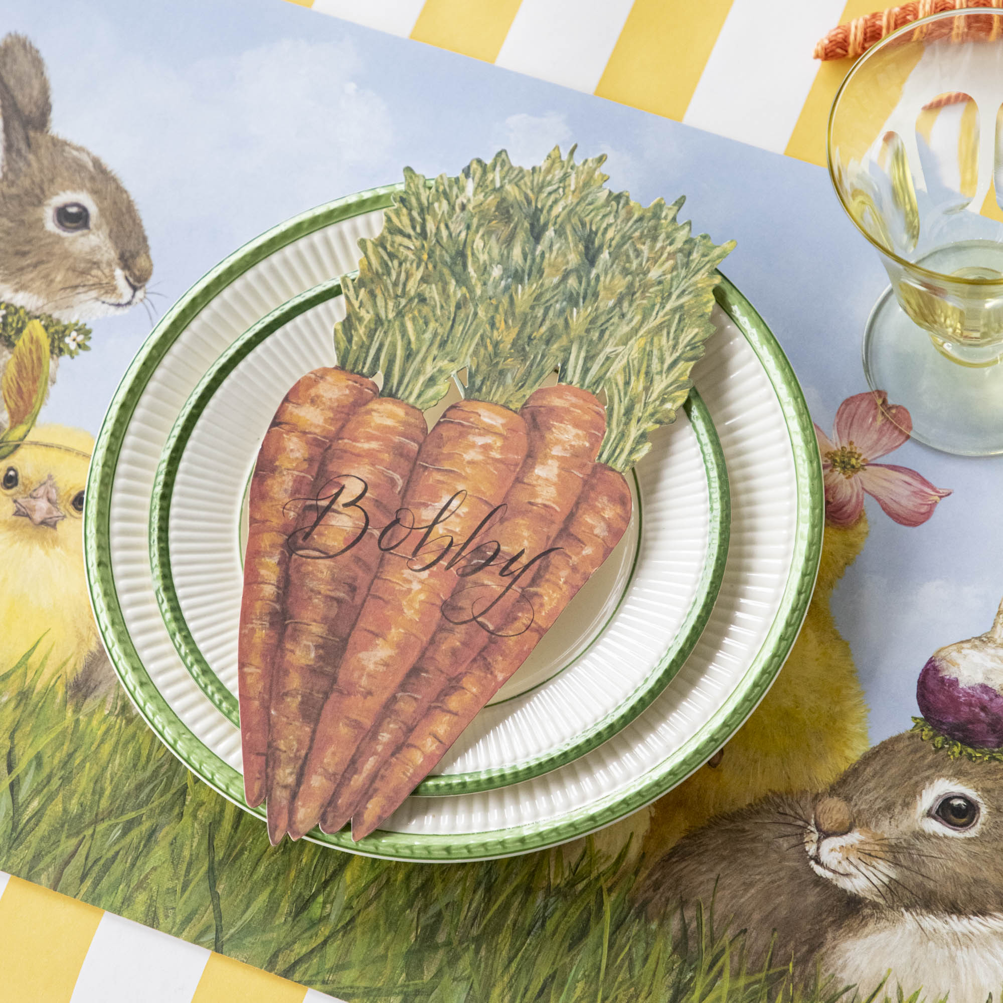 A Carrots Table Accent labeled &quot;Bobby&quot; resting on the plate of a springtime place setting.
