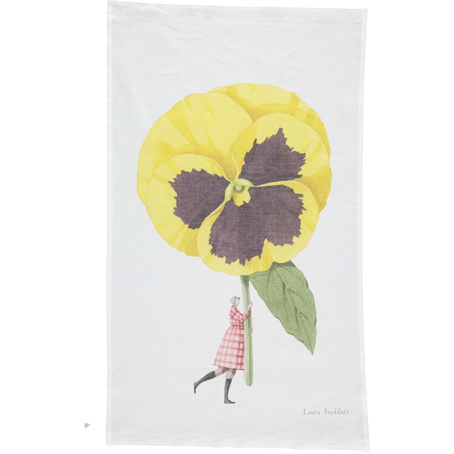 A white tea towel featuring a whimsical illustration of a small woman holding a gigantic yelllow pansy by the stem. Art by Laura Stoddart. 