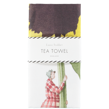 The Laura Stoddart Tea Towel in retail packaging, neatly folded with a white paper belly band.