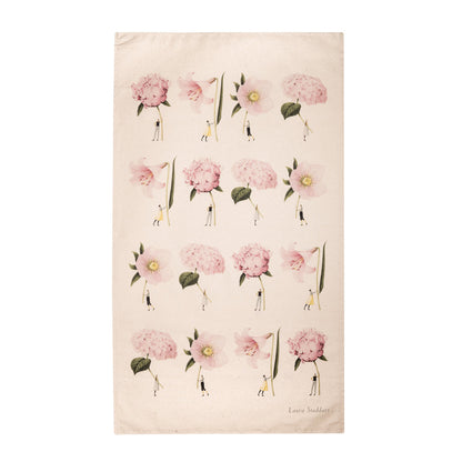 A linen tea towel featuring a pattern of whimsical illustrations of a small people holding  gigantic flowers by the stem. Art by Laura Stoddart. 