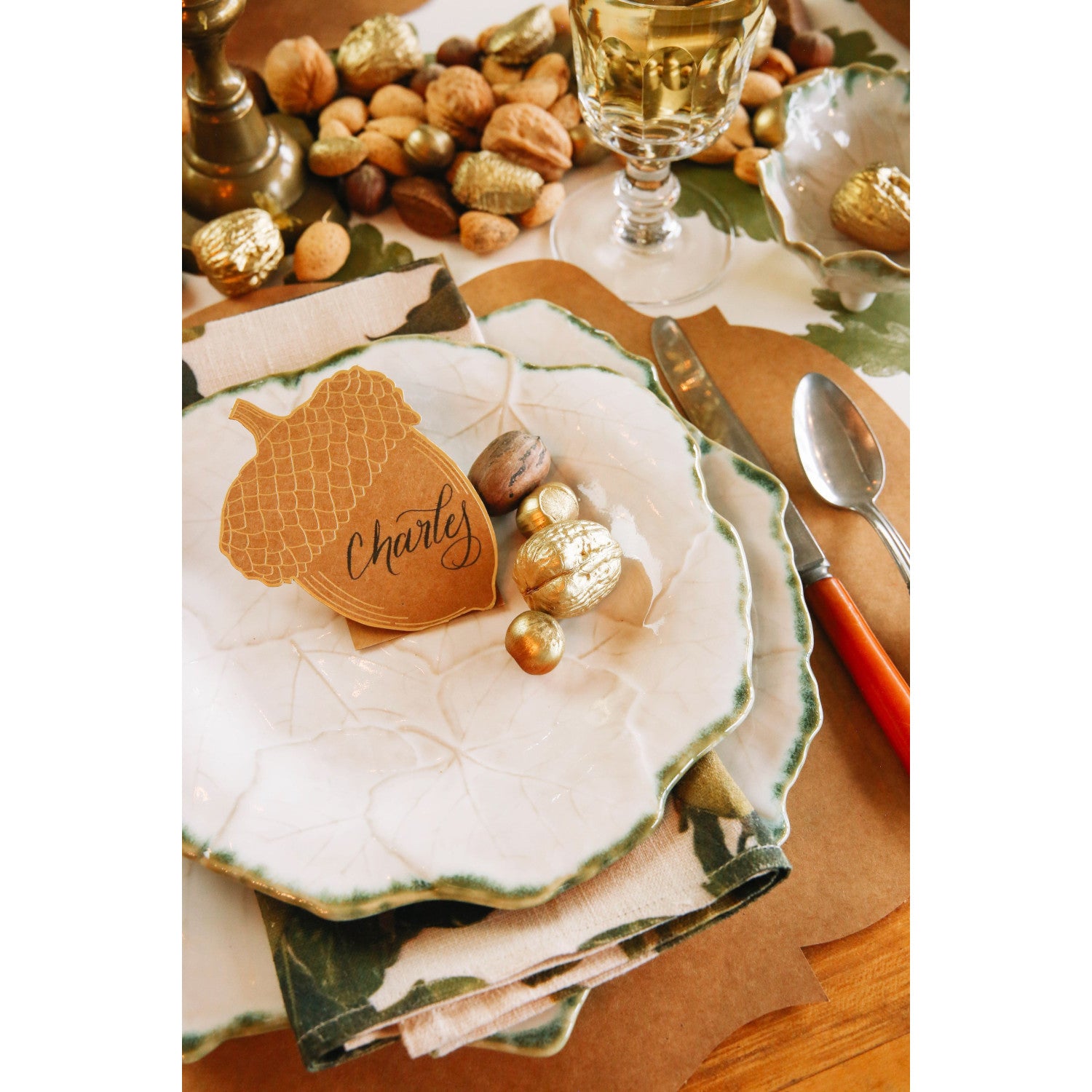 A die-cut kraft paper standing place card of an acorn, featuring gold foil linework.
