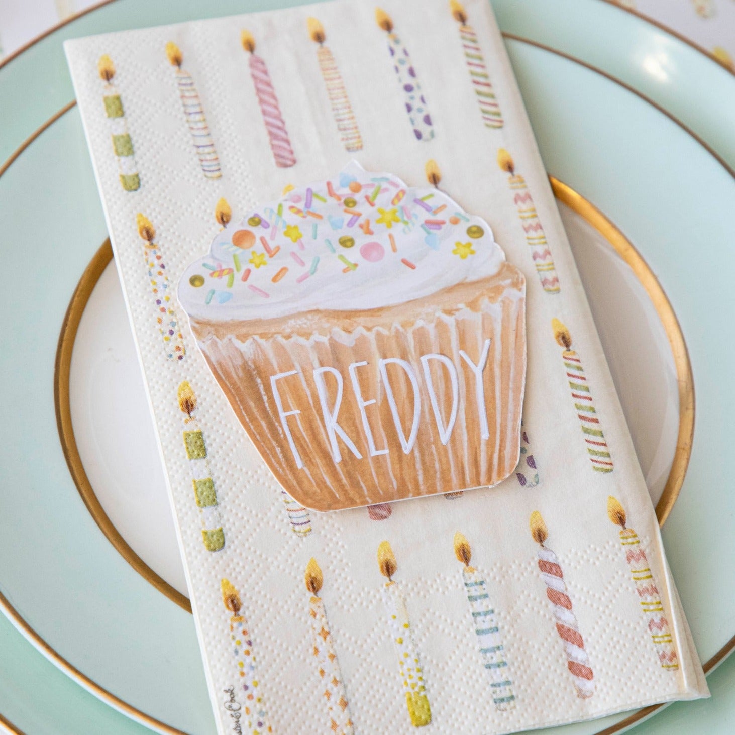 A life-sized Hester &amp; Cook Cupcake Place Card napkin featuring a cupcake and candles, perfect as a party place setting accessory.