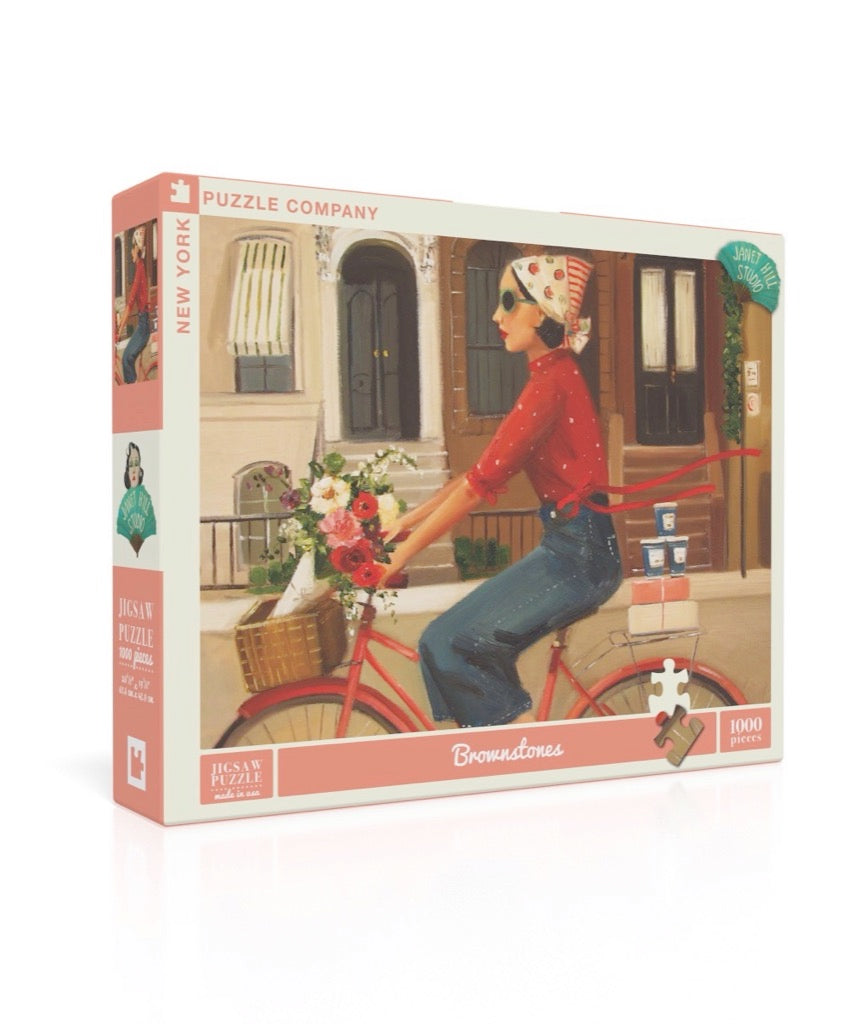 A Brownstones Puzzle of a woman riding a red bicycle with a basket of flowers in front of a building with windows and doors, crafted by Janet Hill, by New York Puzzle Company.