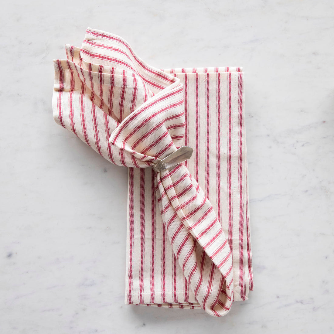 A Taylor Linen Bergen Red Napkin folded on a marble surface for everyday use.