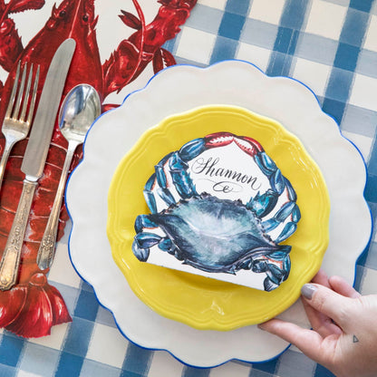 A nautical-themed place setting featuring a Crab Place Card laying flat on a yellow plate.