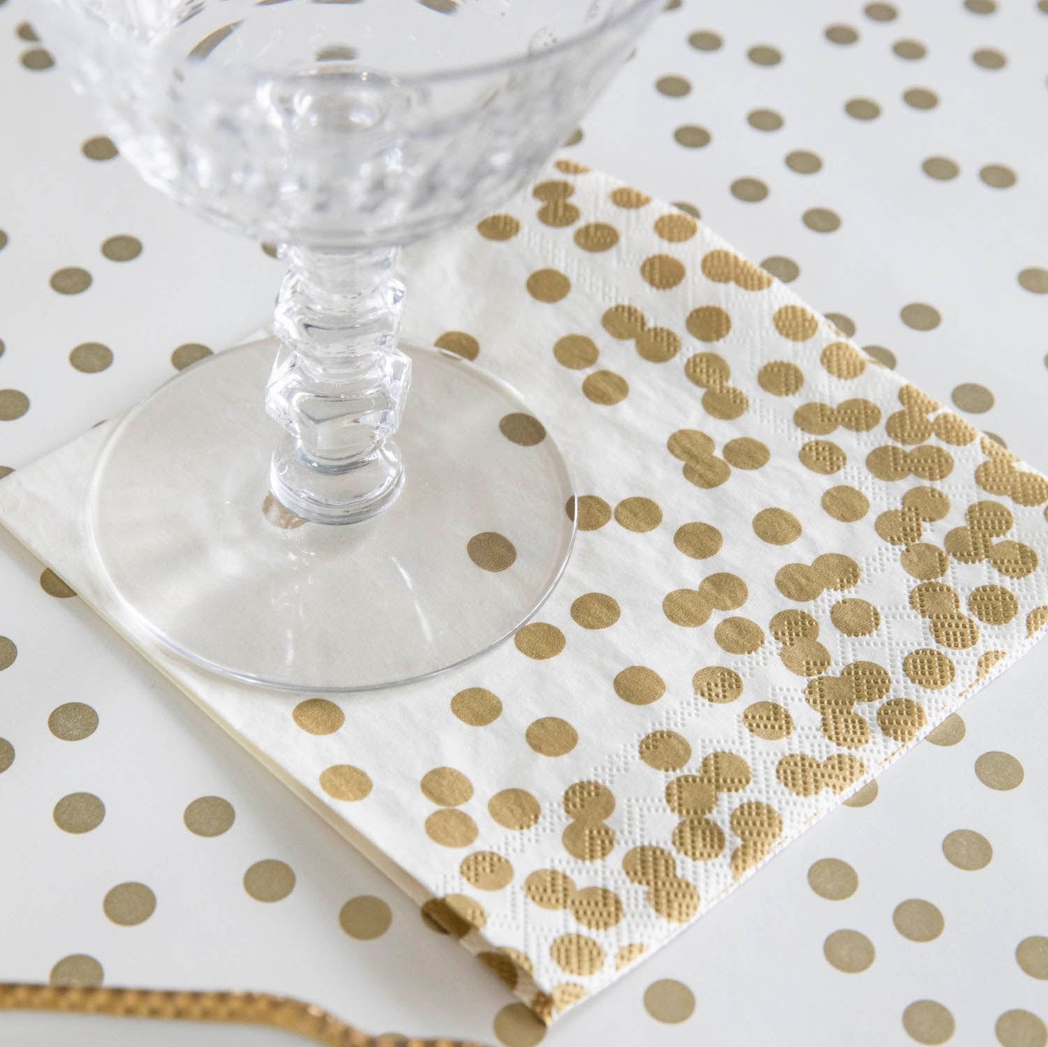 A Gold Confetti Cocktail Napkin under a water glass in an elegant place setting.