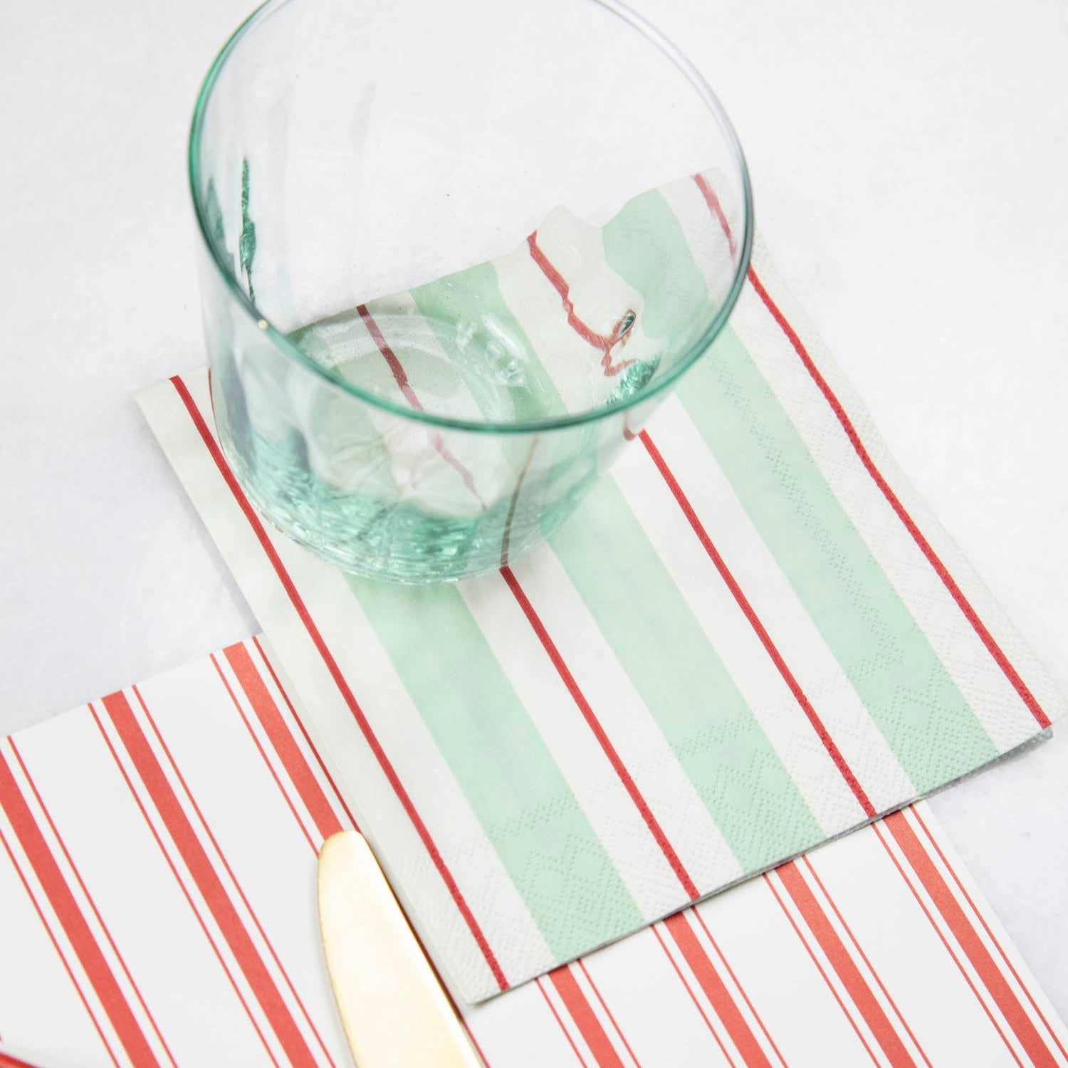 A Seafoam &amp; Red Awning Stripe Cocktail Napkin in an elegant place setting.