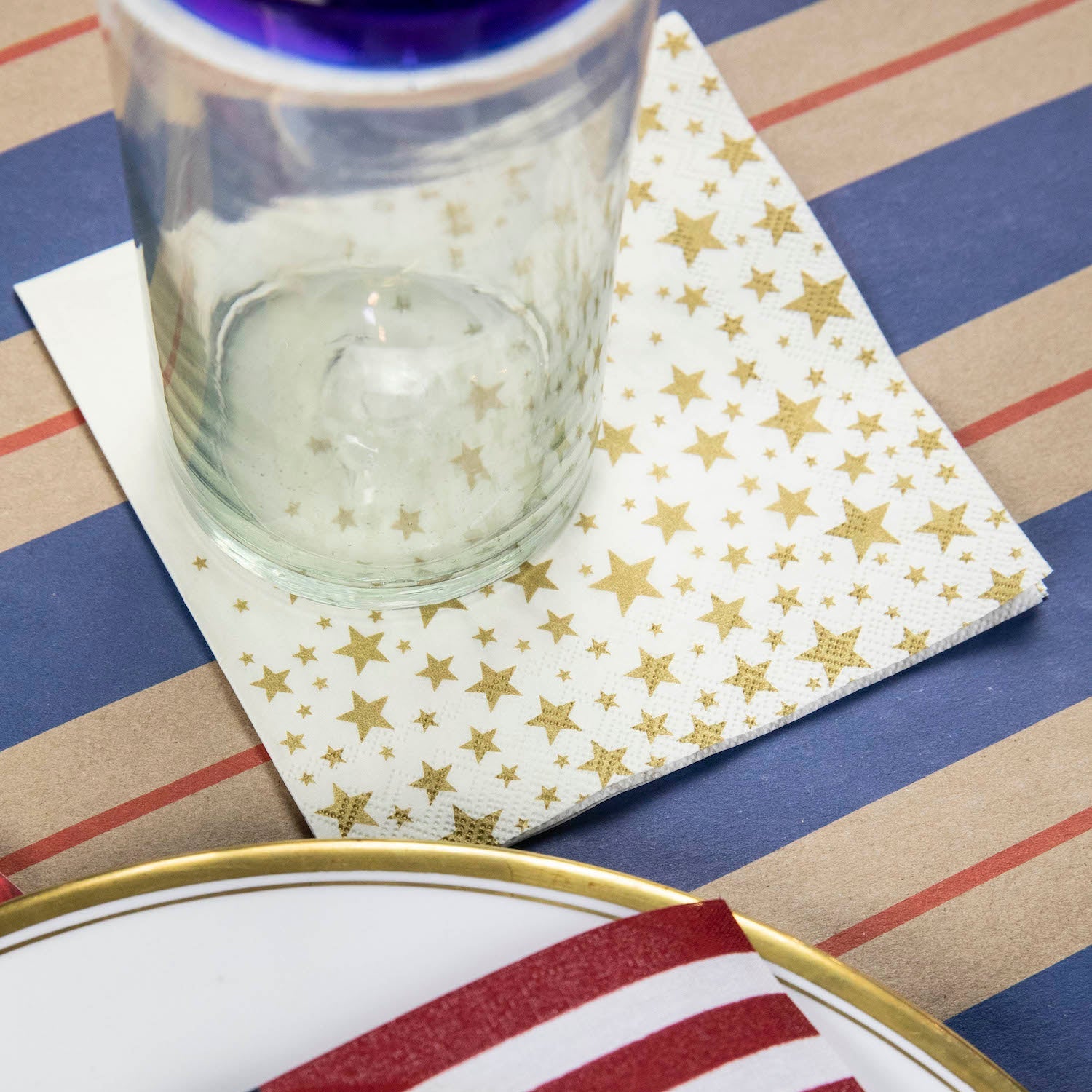 A Shining Star Cocktail Napkin under the water glass of a patriotic place setting.