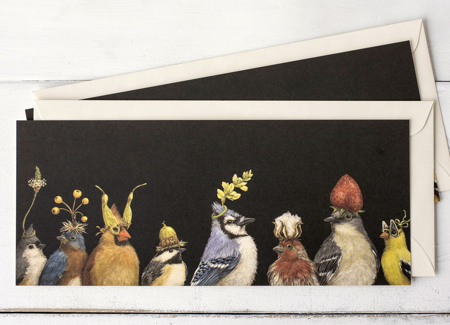 A dark brown greeting card featuring a row of songbirds wearing flowers and botanicals as hats, with the included envelope tucked behind the card. 