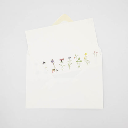 An illustrated Laura Stoddart note card tucked partway into a white envelope. 