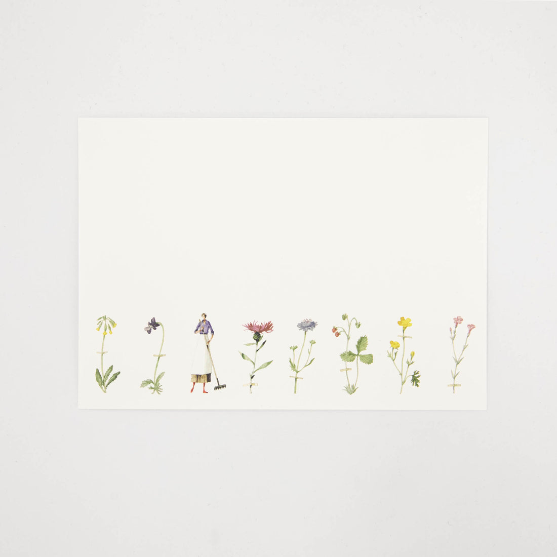 A white note card featuring a row of illustrated wildflowers across the bottom of the card, and a woman holding a rake. 