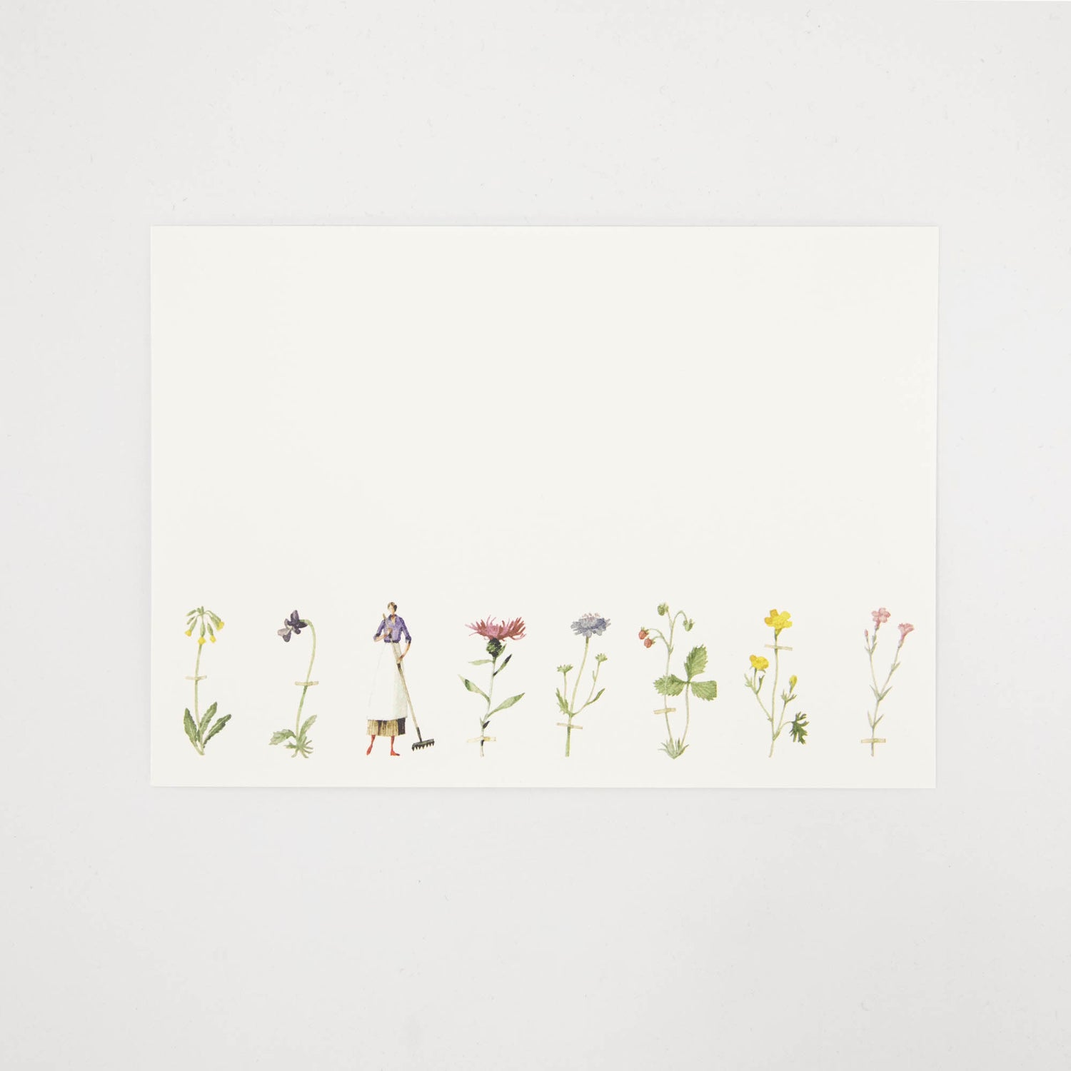 A white note card featuring a row of illustrated wildflowers across the bottom of the card, and a woman holding a rake. 