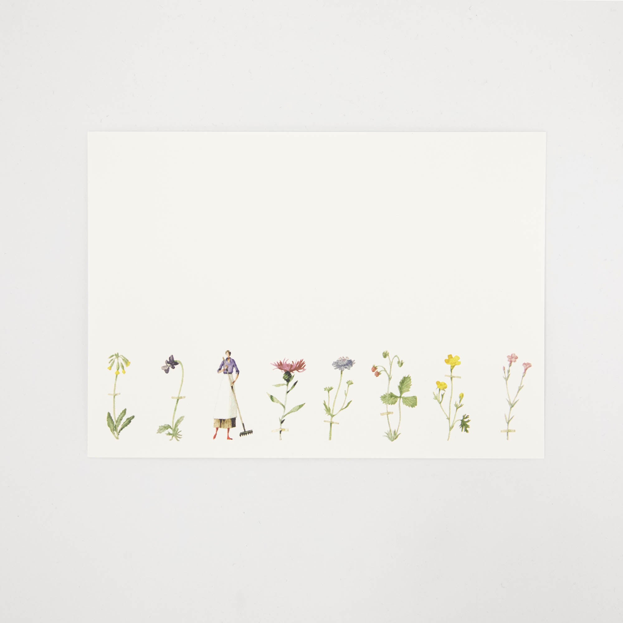 A white note card featuring a row of illustrated wildflowers across the bottom of the card, and a woman holding a rake. 