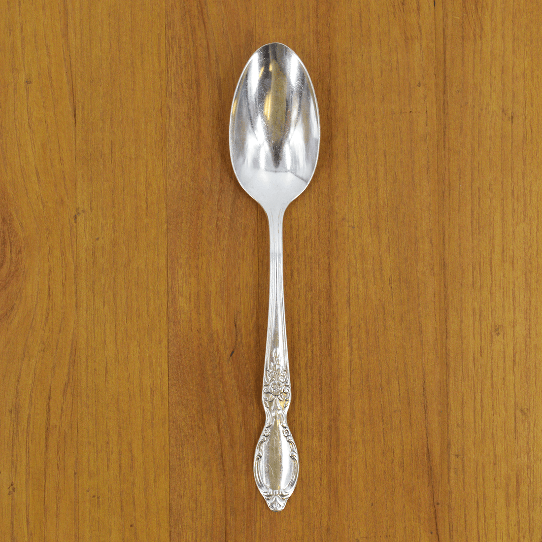 A Hester &amp; Cook vintage silver-plate serving spoon sits on top of a green napkin.