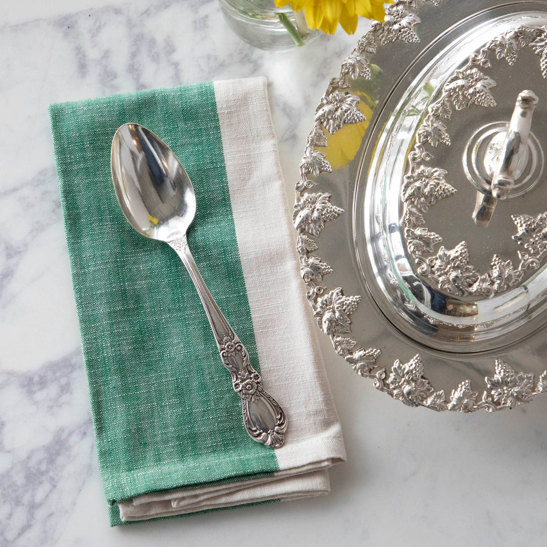 A Hester &amp; Cook vintage silver-plate serving spoon sits on top of a green napkin.