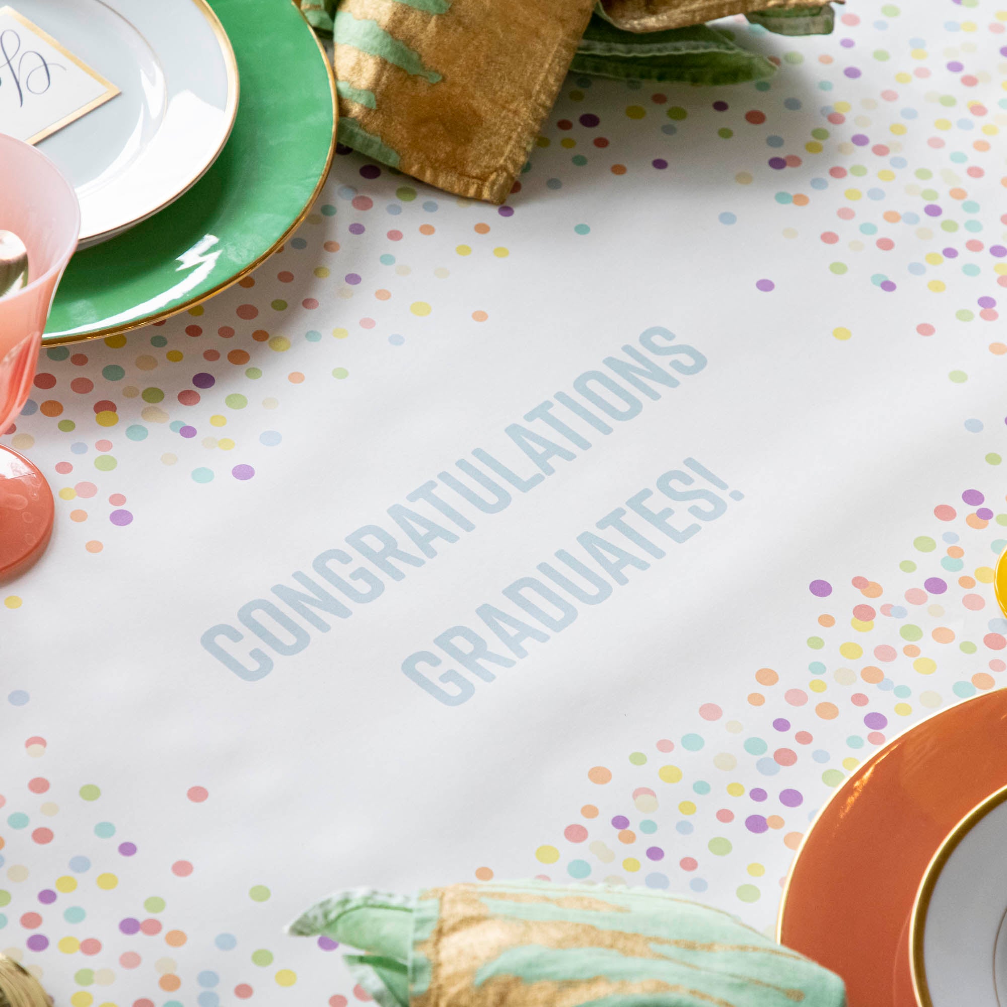 The Confetti Sprinkles Personalized Runner under a festive table setting, with &quot;CONGRATULATIONS GRADUATES!&quot; printed in light blue.