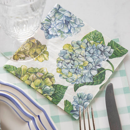 A Hydrangea Cocktail Napkin under the glass of an elegant place setting.