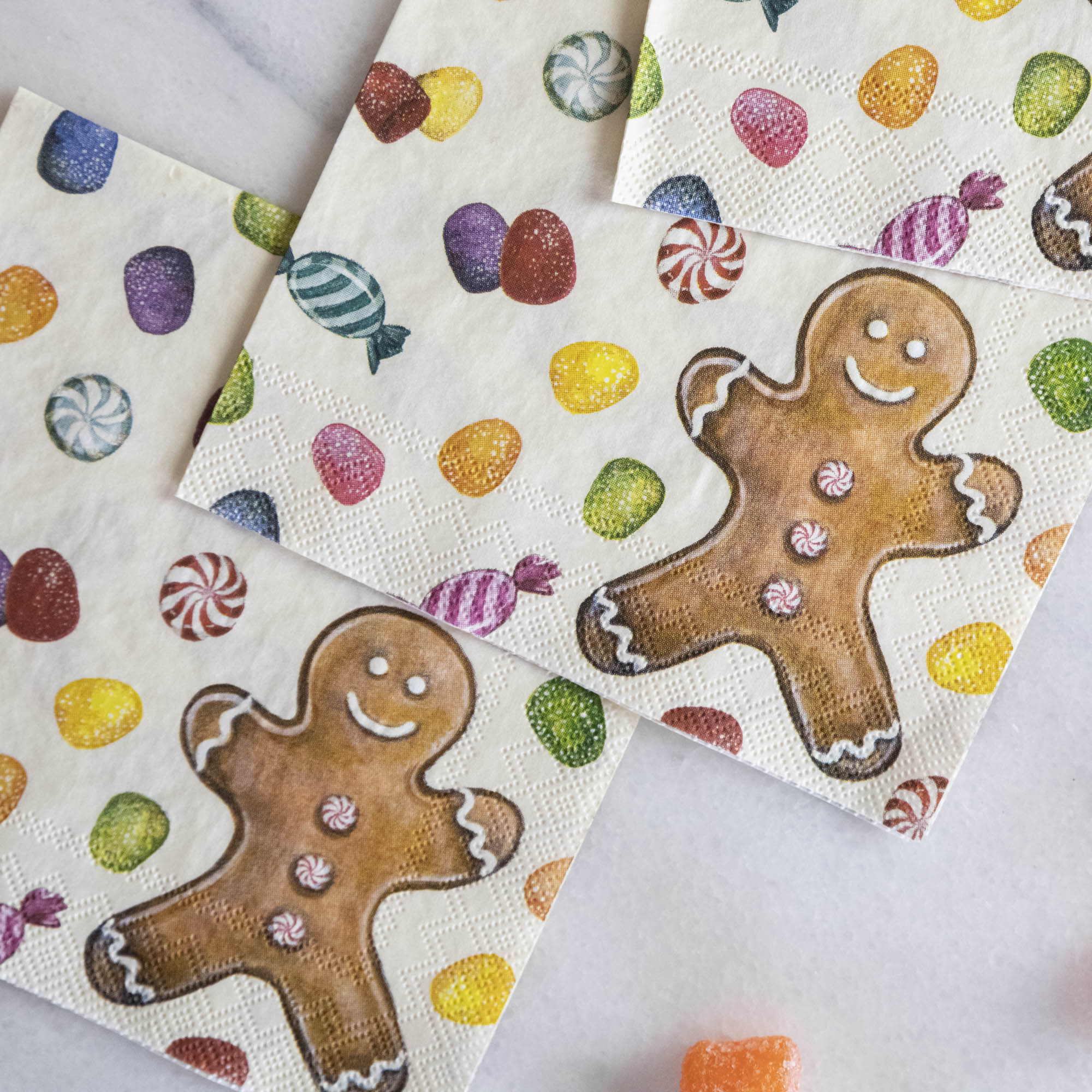 Close-up of three Gingerbread Cocktail Napkins, overlapping on a white table.