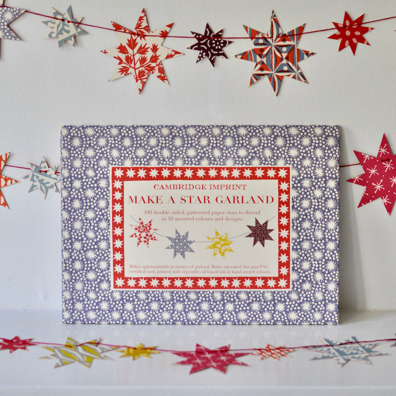 A craft kit titled &quot;Make a Star Garland&quot; by Cambridge Imprint displayed on a shelf with FSC-certified card, star decorations around.