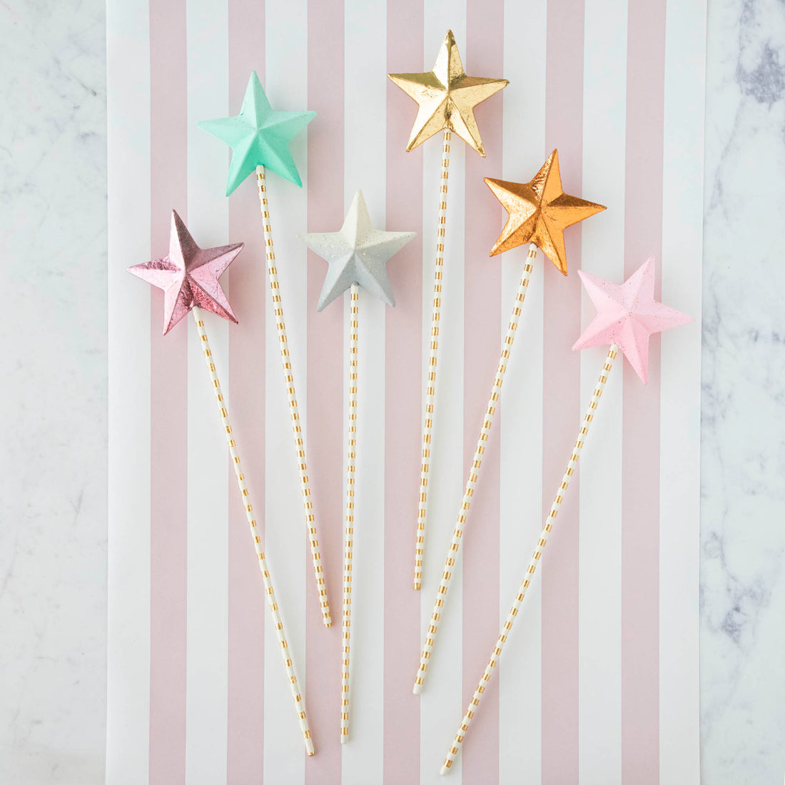 Five Glitterville Magic Wands on a striped background.