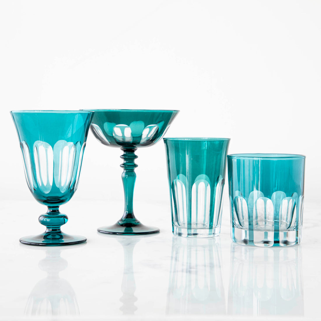 Set of four bespoke Rialto Millicent (Dark Green) glasses by SIR/MADAM on a reflective surface against a white background.